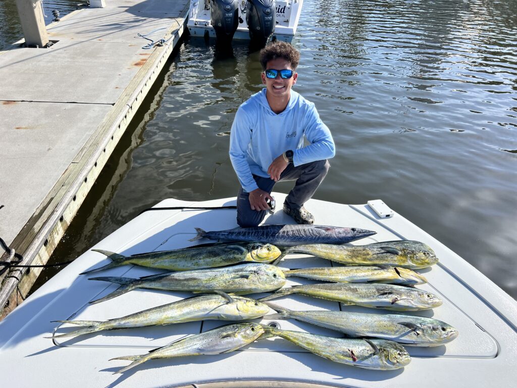 a boy poses with several fish on a dock