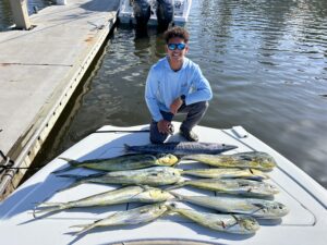 a boy poses with several fish on a dock