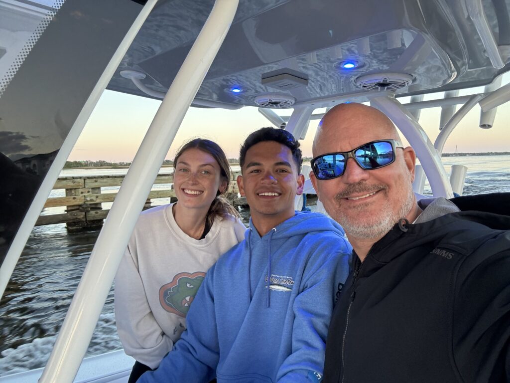 three people smile while sitting on a boat